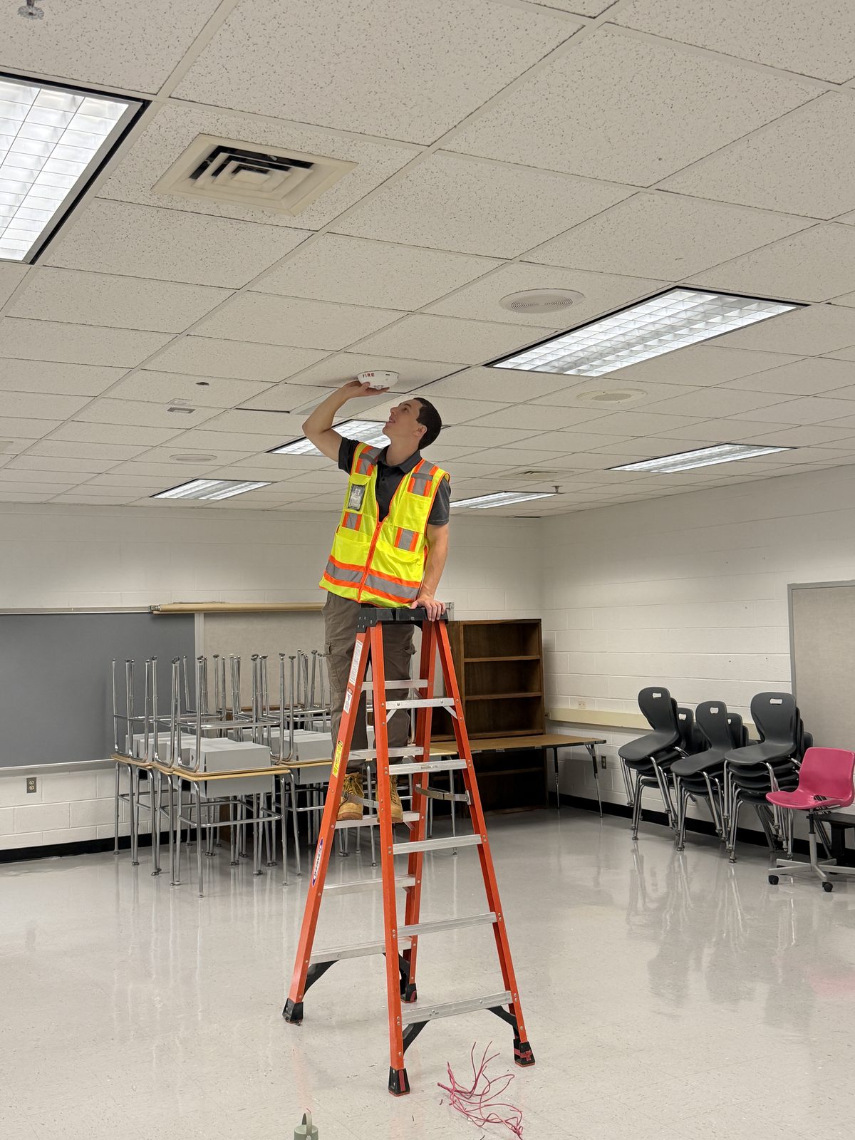 Installing a ceiling-mounted smoke detector in a classroom