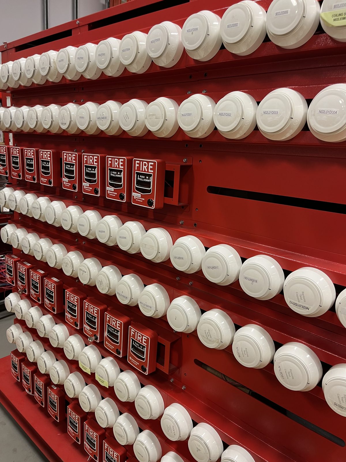 Racks of smoke detectors and manual pull stations staged for installation