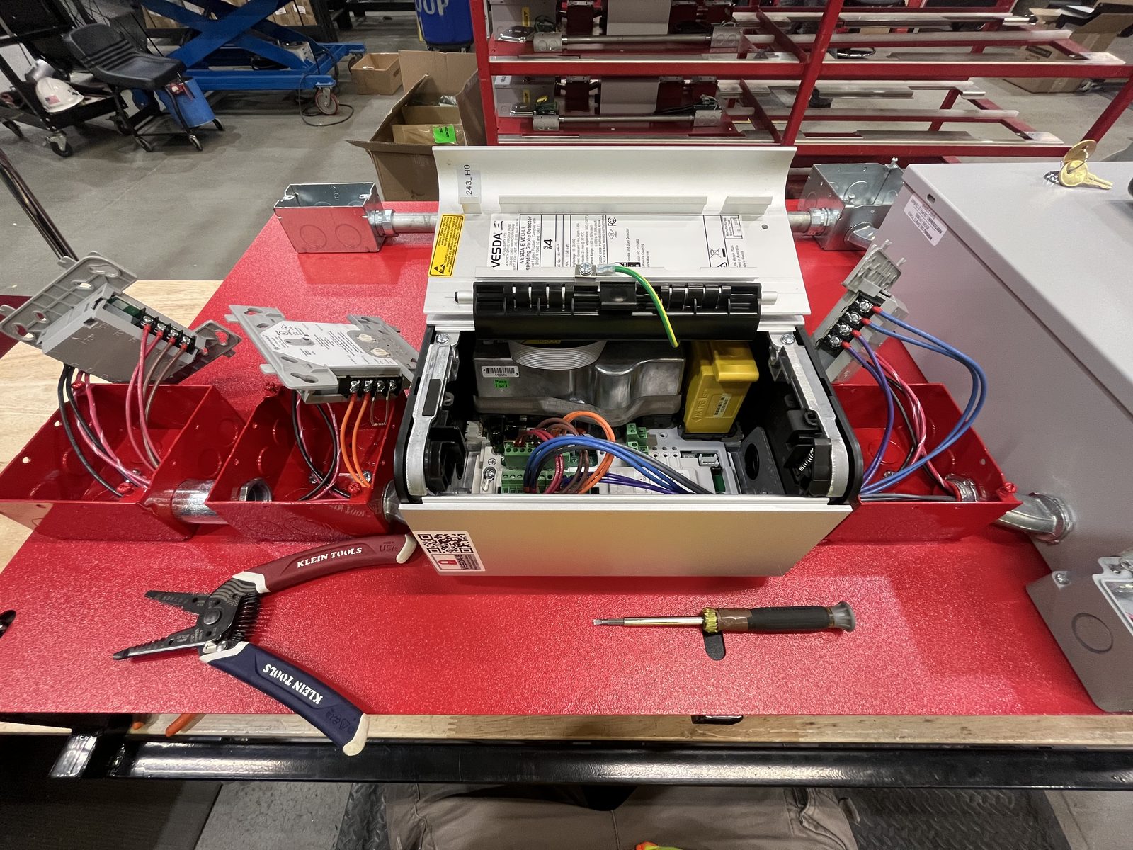 VESDA aspirating smoke detector open on the bench with field wiring run to junction boxes